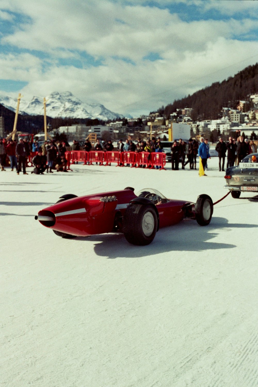 a red car pulling a trailer on a snowy surface