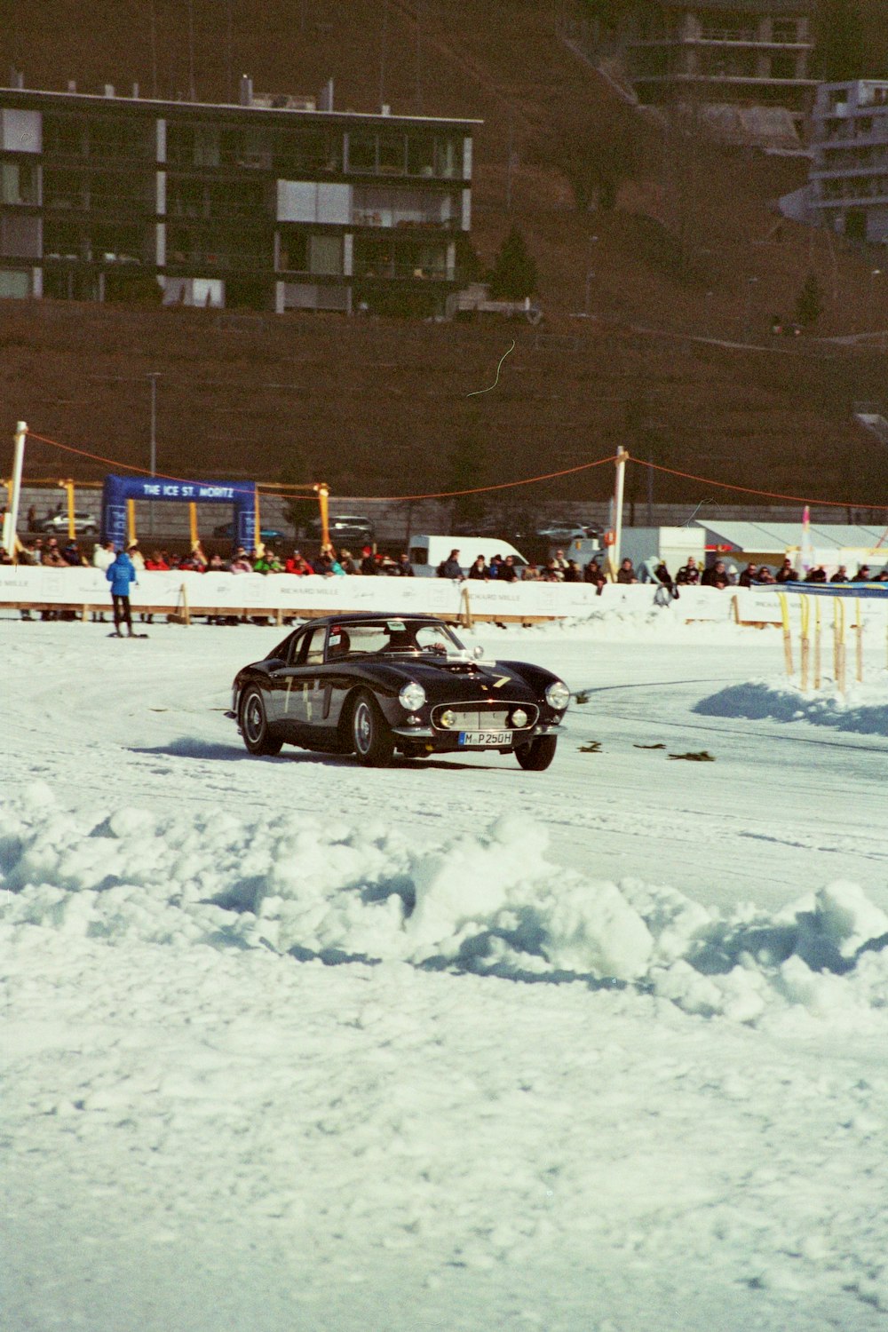 a car driving through the snow in front of a building