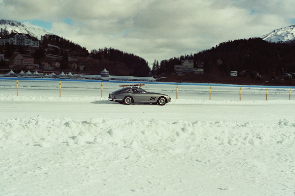 a car parked on a snowy road in front of a mountain