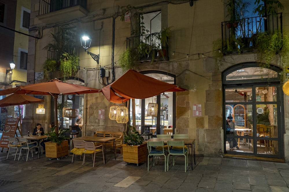 a restaurant with tables and umbrellas outside at night