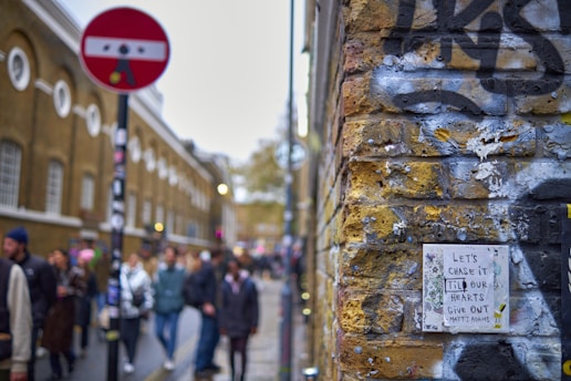 A vibrant street scene showcasing colorful street art on a brick wall with people walking by.