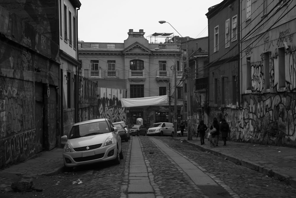 a black and white photo of a car parked on a cobblestone street