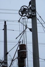 Electrical utility poles with wires and gears are visible. The setup includes weights that may be part of an industrial mechanism or telecommunication infrastructure.