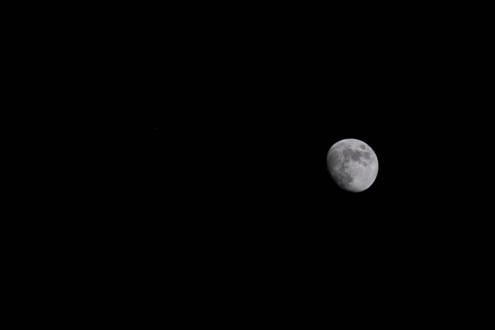 a full moon is seen in the dark sky