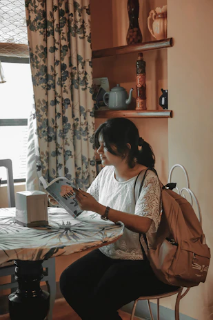 A young woman reading 'the most excellent way' in a cozy nook, a journal and pen beside her.