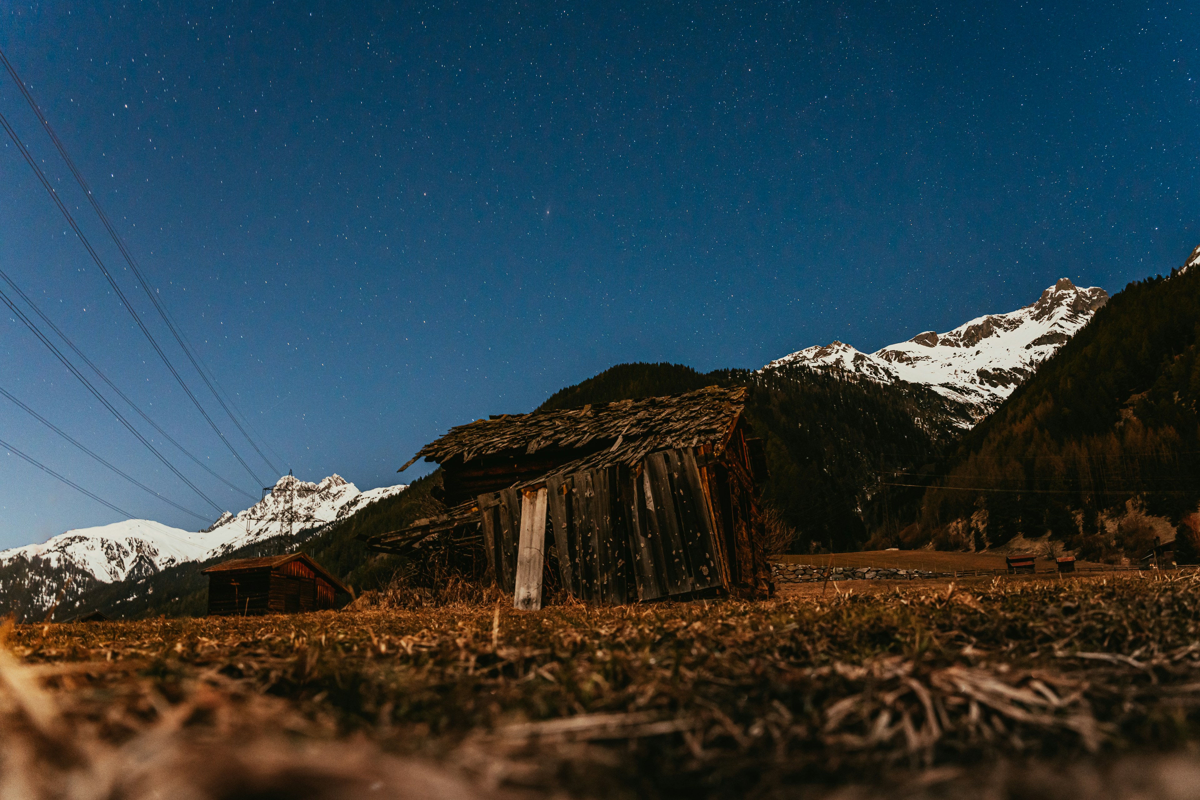 a barn in the middle of a field with mountains in the background