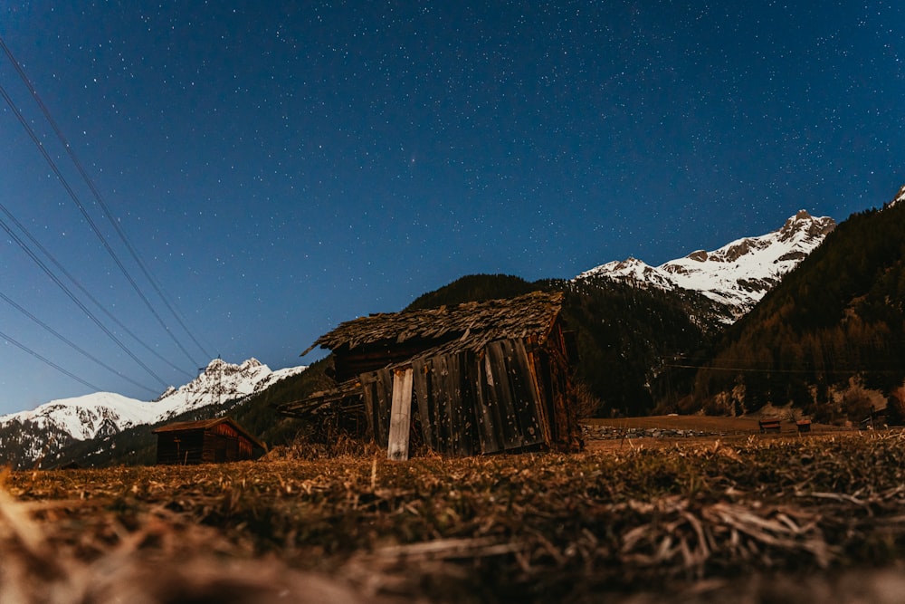 a barn in the middle of a field with mountains in the background