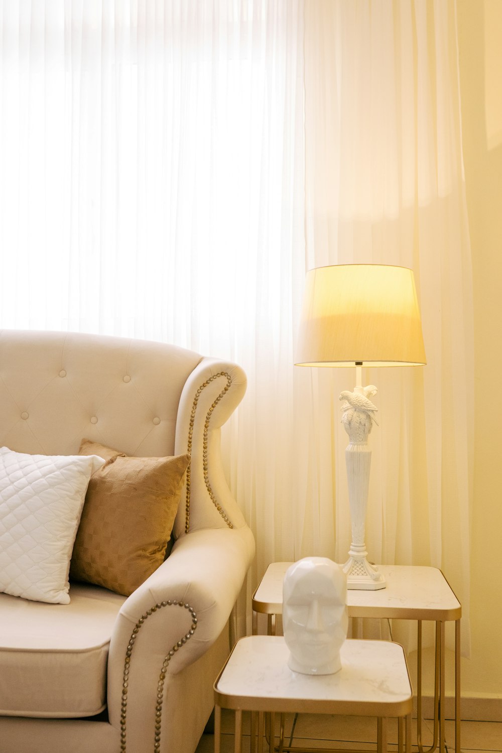 a white couch sitting next to a table with a lamp on top of it