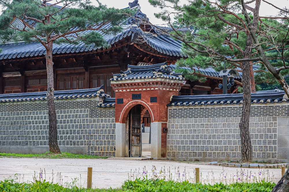 a brick building with a gate and trees in front of it