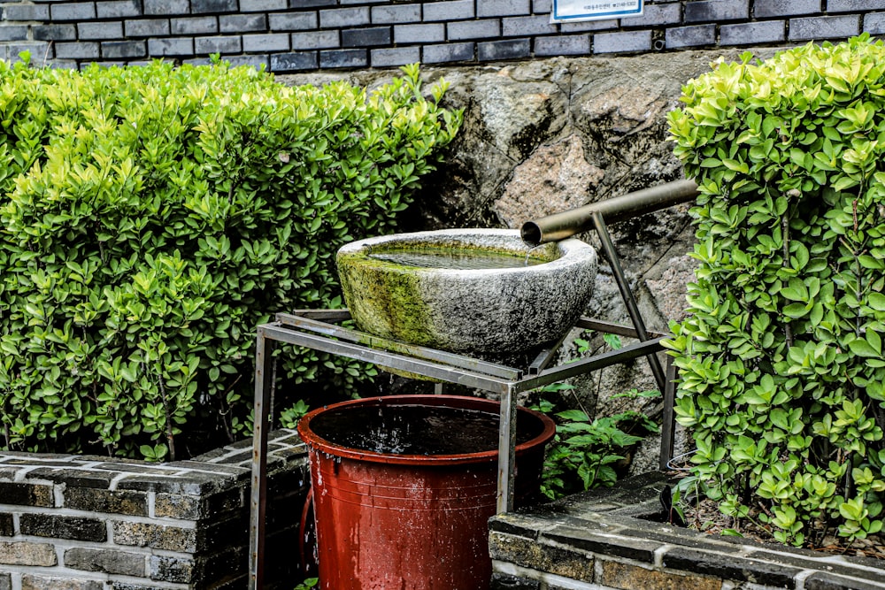 a bucket of water sitting on top of a metal stand next to a brick wall