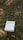 A book titled 'The Meaning of Marriage' by Timothy Keller is placed on the grass. The background consists of green and brown grass, with fallen leaves scattered around.