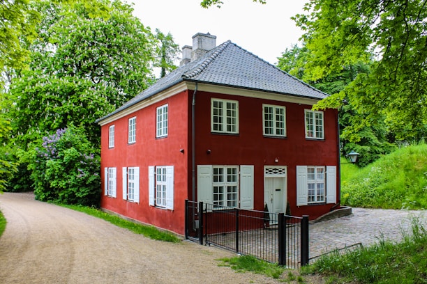 Charming two-story house with a wooden porch and a lush garden in front.