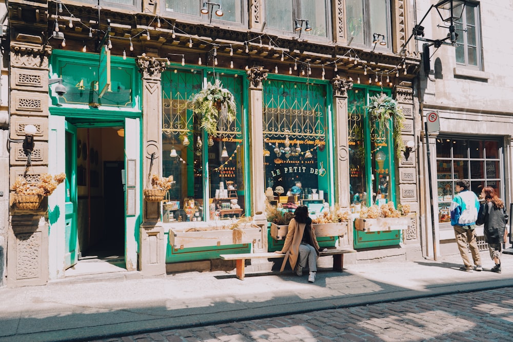 a person sitting on a bench in front of a store