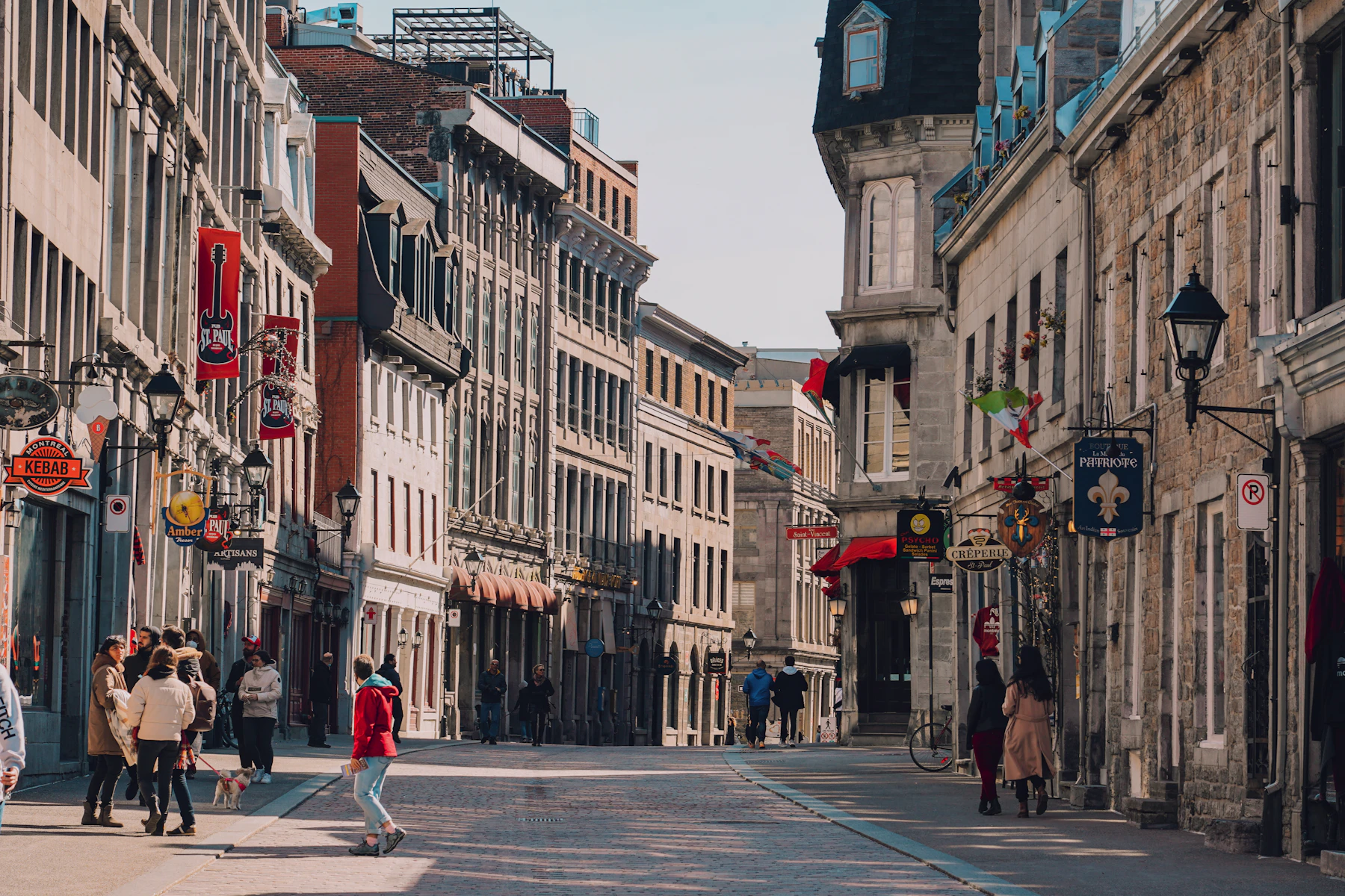 People walk on a Montréal street lined with tall buildings.