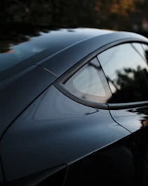 Candid cinematic shot of a driver interacting naturally with a sleek car in an urban setting.