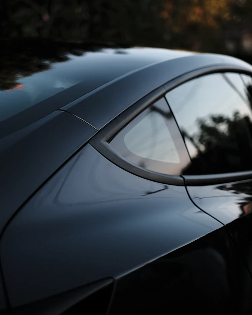 Candid cinematic shot of a driver interacting naturally with a sleek car in an urban setting.