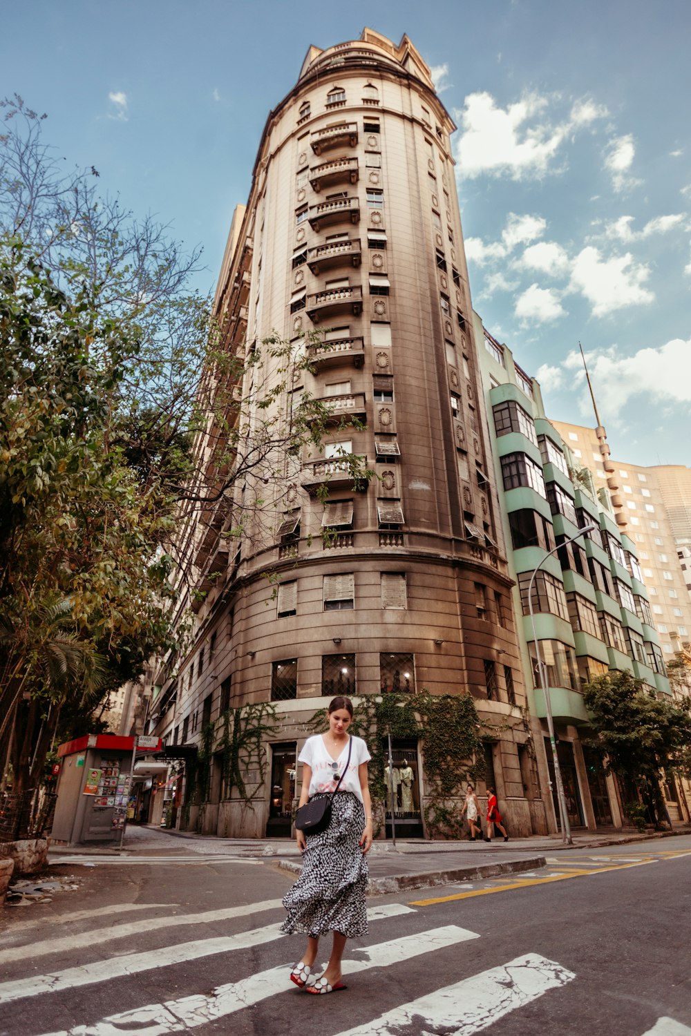 a woman crossing the street in front of a tall building