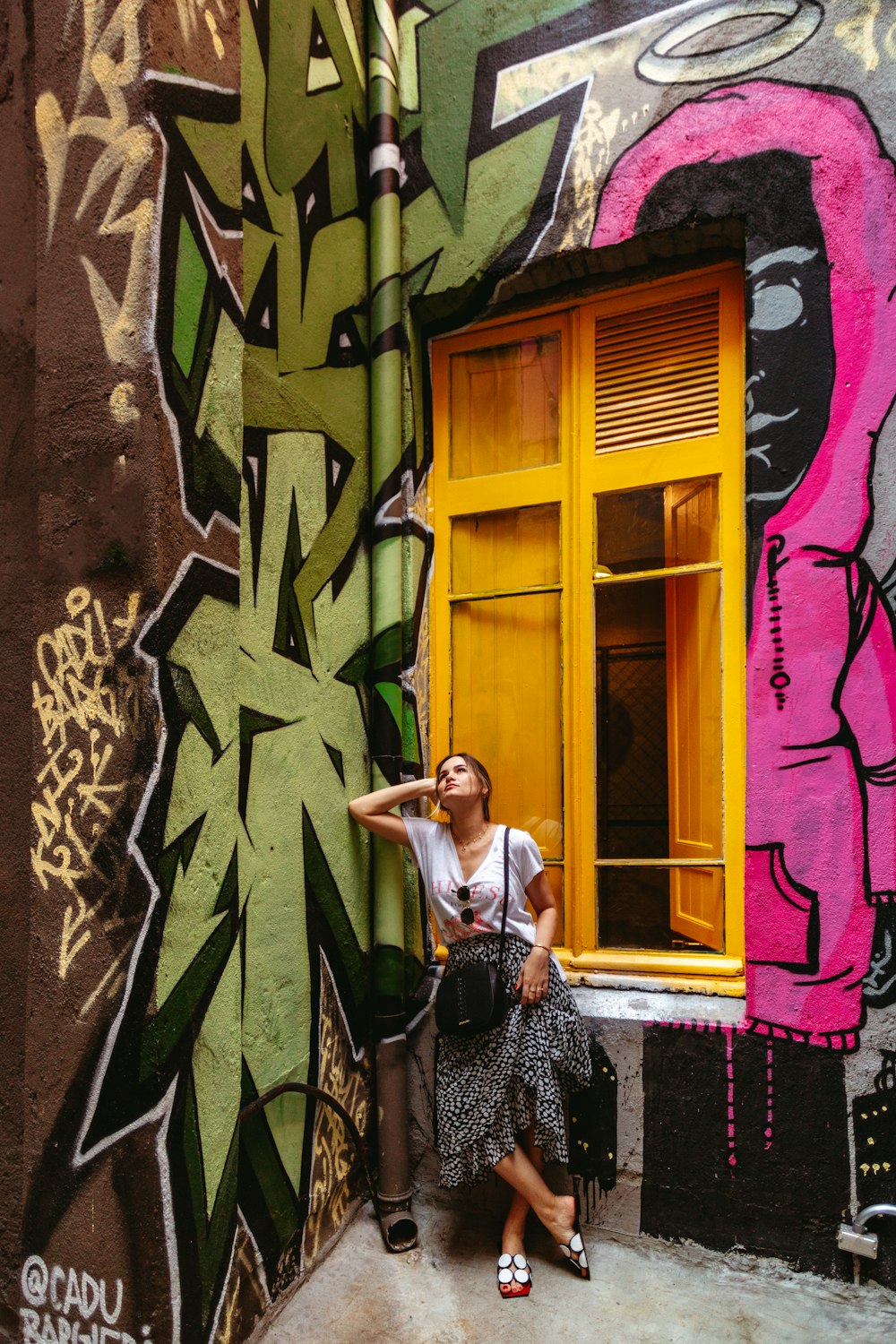 a woman leaning against a wall with graffiti on it