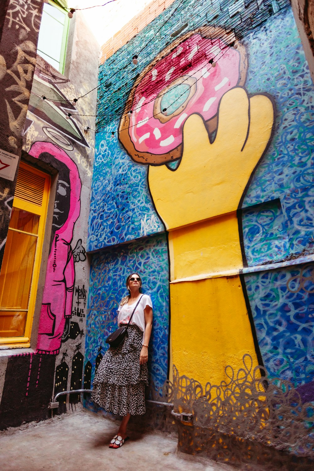 a woman standing in front of a mural of a donut