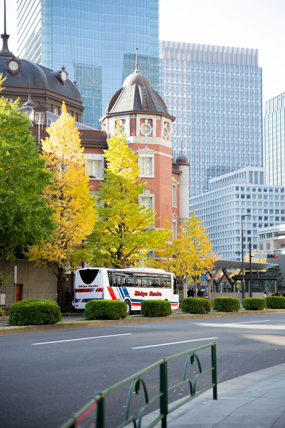 a white bus driving down a street next to tall buildings