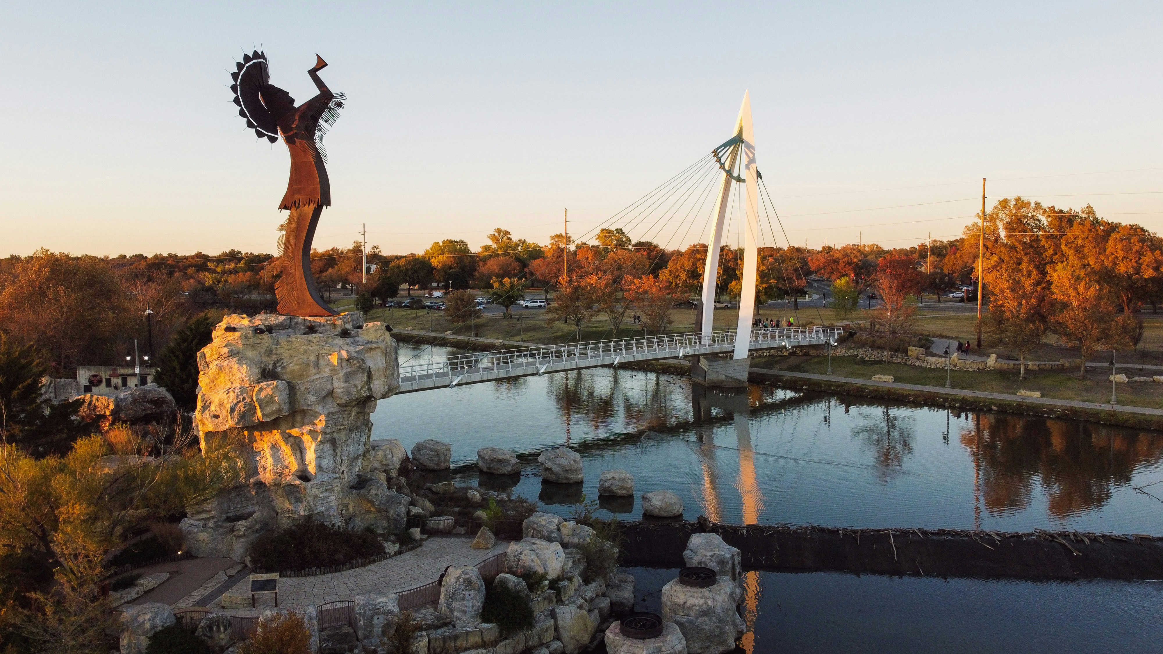 a statue of a woman holding a bird next to a river