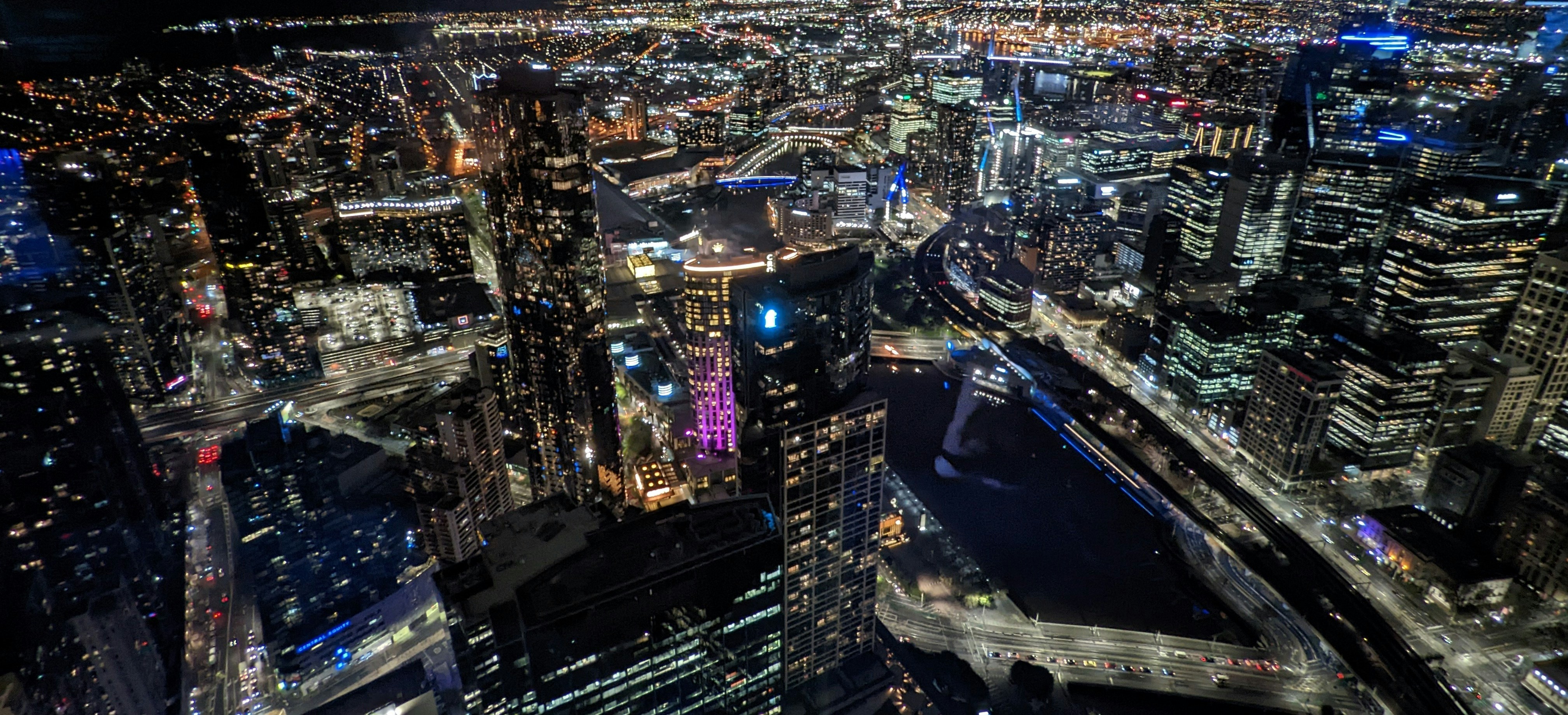 Bright aerial city skyline with glowing buildings and colorful lights, well-lit urban game environment