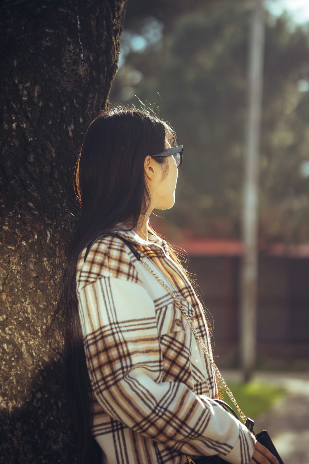 a woman standing next to a tree wearing sunglasses