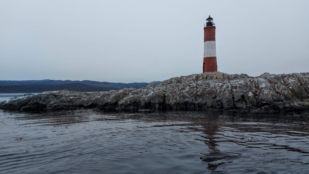 a red and white light house sitting on top of a rock