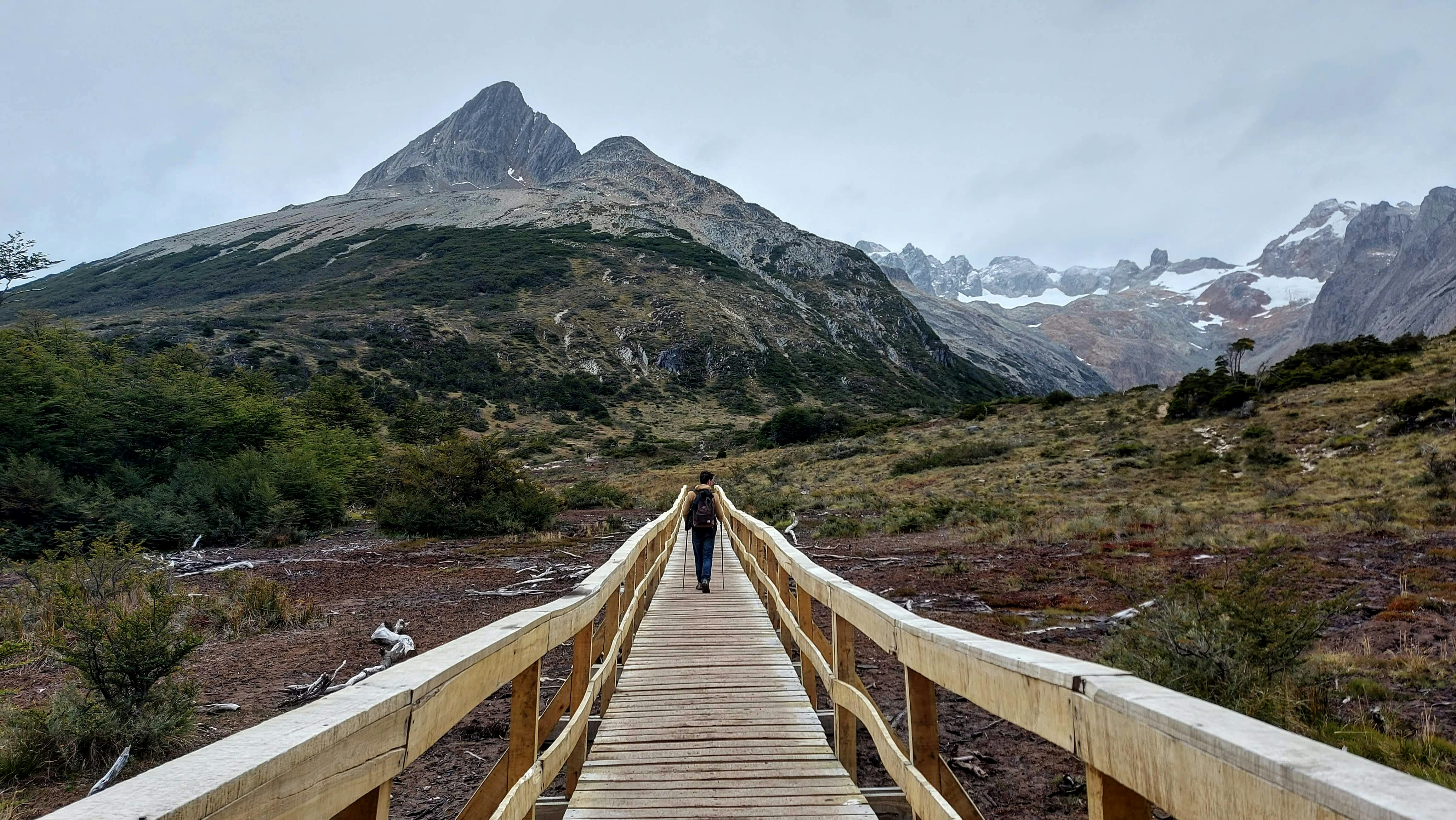 Hiker crossing a wooden bridge in Patagonia, representing safety planning and emergency coverage
