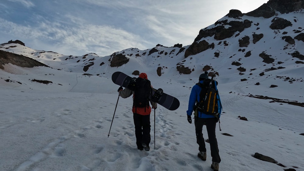 a couple of men walking across a snow covered slope