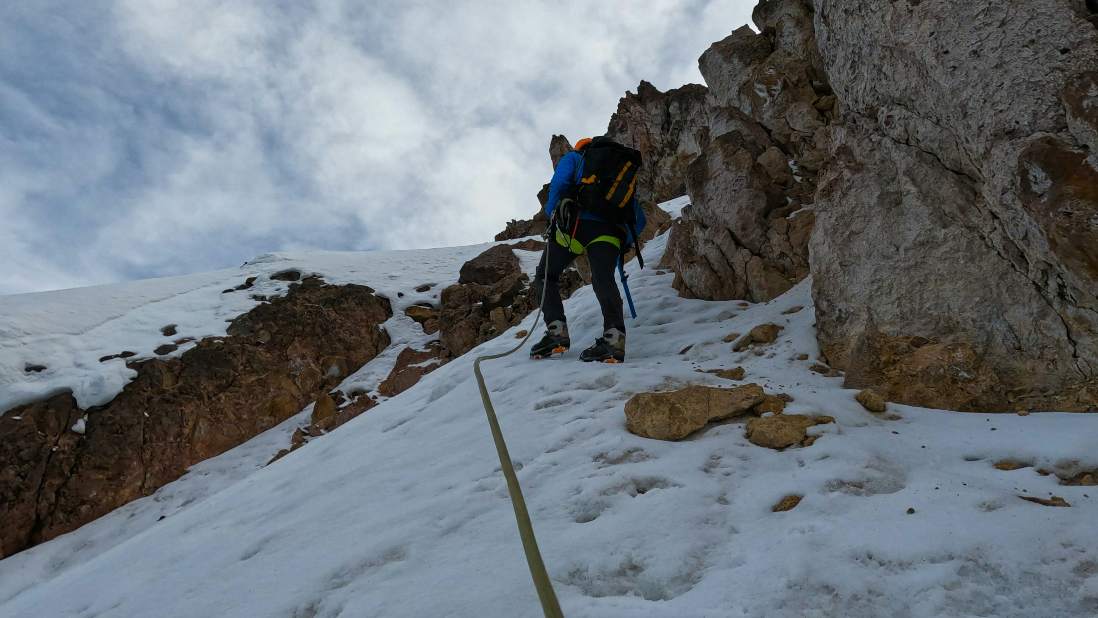 a man climbing up the side of a snow covered mountain