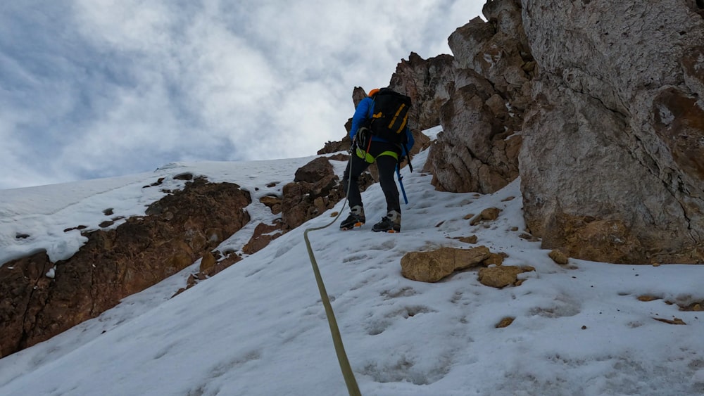 a man climbing up the side of a snow covered mountain