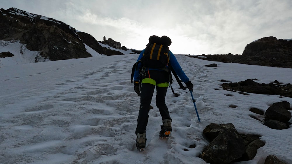 Eine Person, die mit Skiern einen verschneiten Hügel hinaufgeht