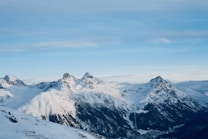 Snow-covered mountain peaks under a clear blue sky create a breathtaking alpine landscape. The rugged terrain and serene atmosphere suggest a remote and peaceful environment.