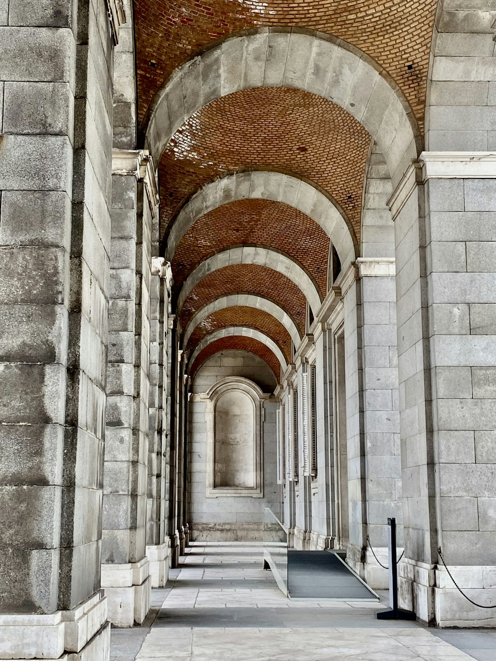 um longo corredor com um teto de tijolos e arcos