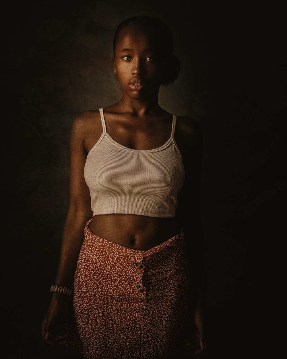 a woman standing in a dark room wearing a white tank top