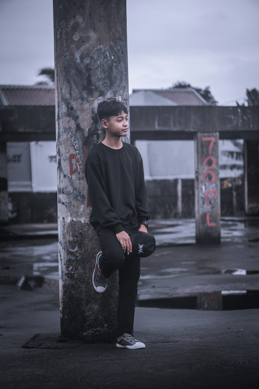 a young man sitting on a pole in a parking lot