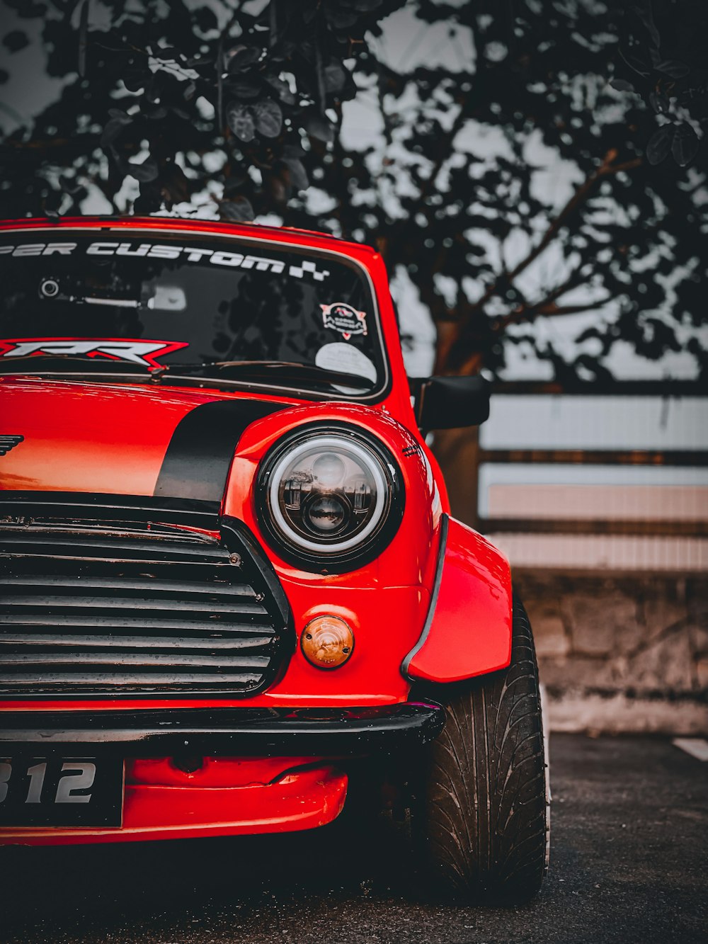 a red car parked in a parking lot next to a tree