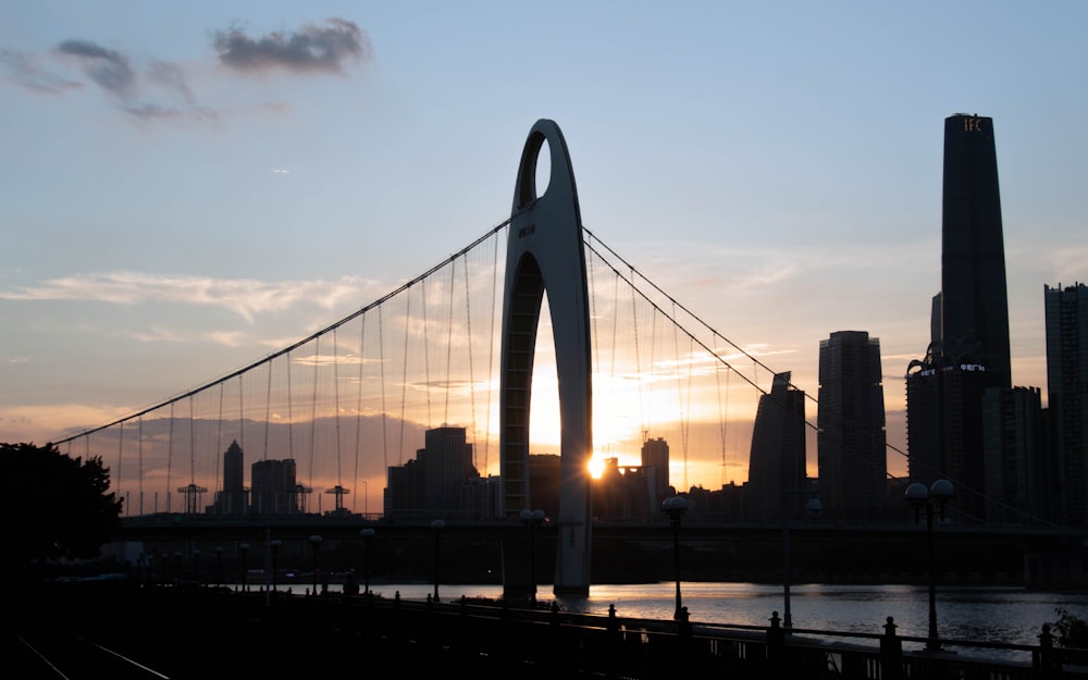 the sun is setting behind a bridge in a city