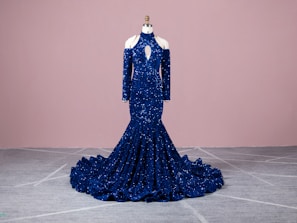 An elegant evening gown in deep blue, showcased on a mannequin in natural light.
