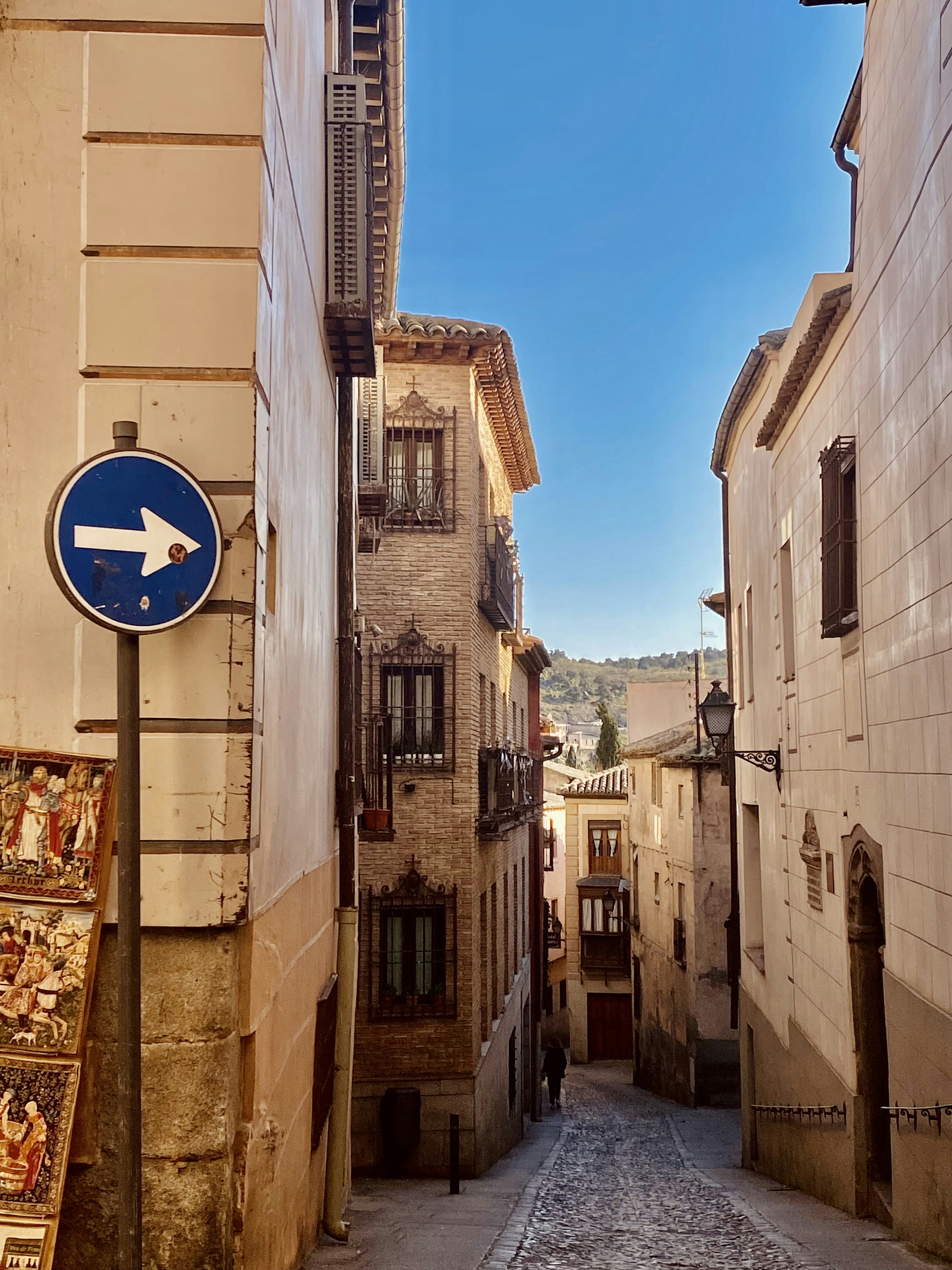a narrow street with a blue sign on the side of it