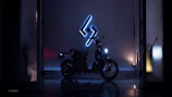 A sleek electric motorcycle showcased in an industrial warehouse lit by electric blue neon lights.