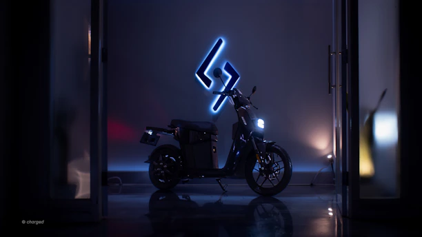 An electric motorcycle parked under soft blue lighting, highlighting its modern design.