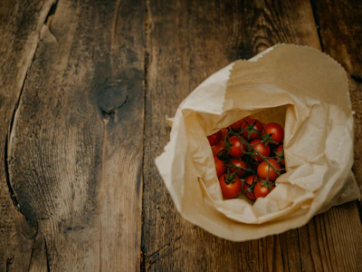 Close-up of a rustic wooden table topped with fresh tomatoes and basil from local farmers.