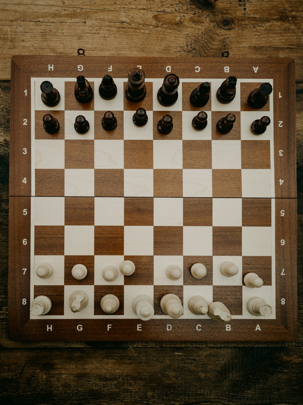 a wooden chess board with white and black pieces