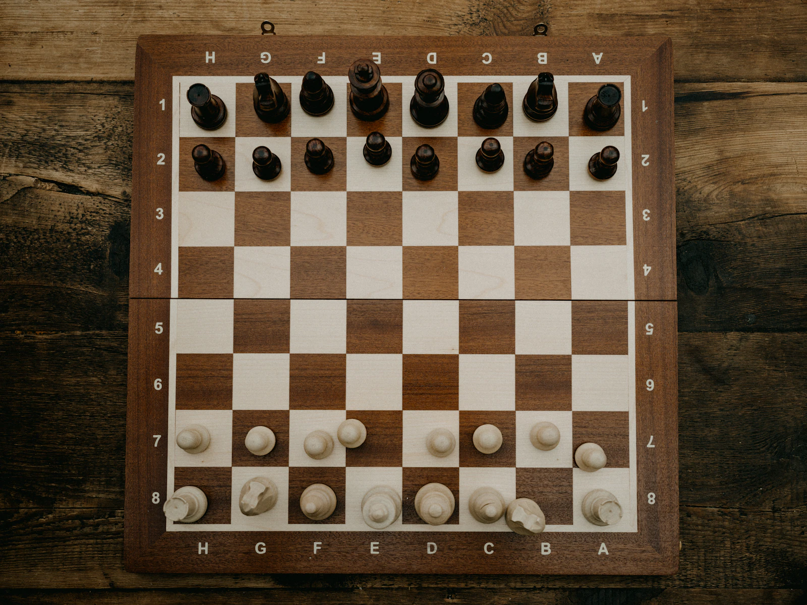 A wooden chess board mid-game with pieces in play