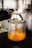 A close-up view of an espresso machine pouring fresh espresso into a small glass cup. The rich crema is visible as the coffee fills the container. The metallic finish of the machine contrasts with the brown hues of the espresso.