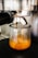A close-up view of an espresso machine pouring fresh espresso into a small glass cup. The rich crema is visible as the coffee fills the container. The metallic finish of the machine contrasts with the brown hues of the espresso.