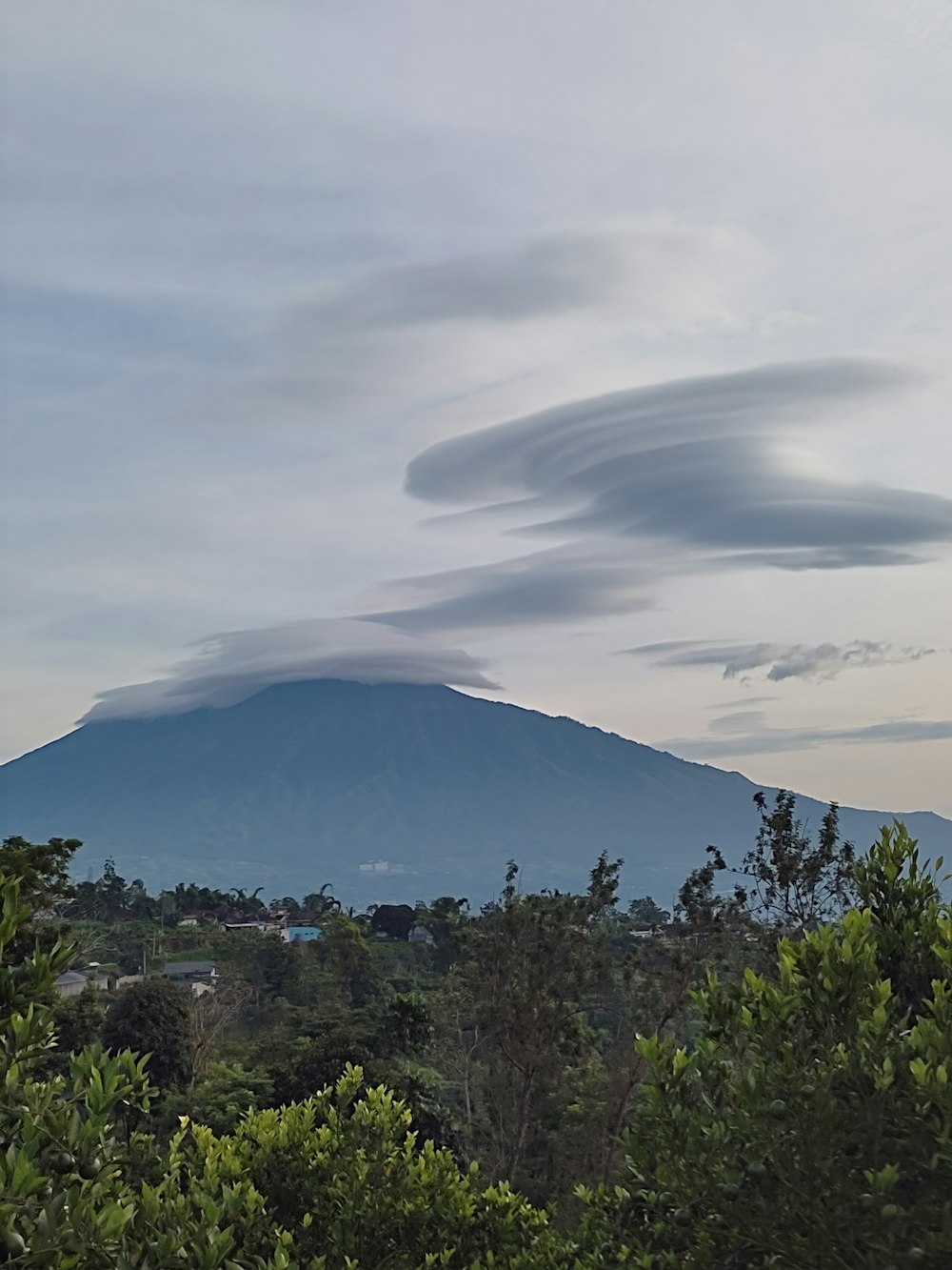 a large cloud is in the sky over a mountain