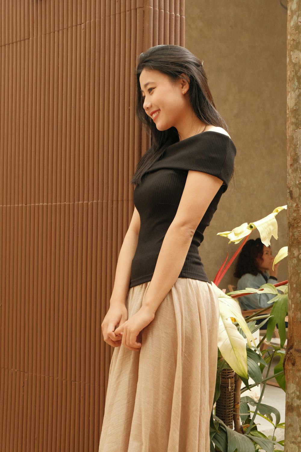 a woman in a black top and tan skirt